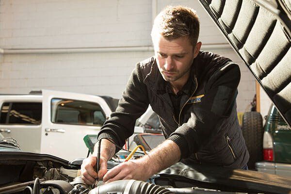 A Man is Working on the Engine of a Car in a Garage — A Plus Automotive Electrical in Lavington, NSW