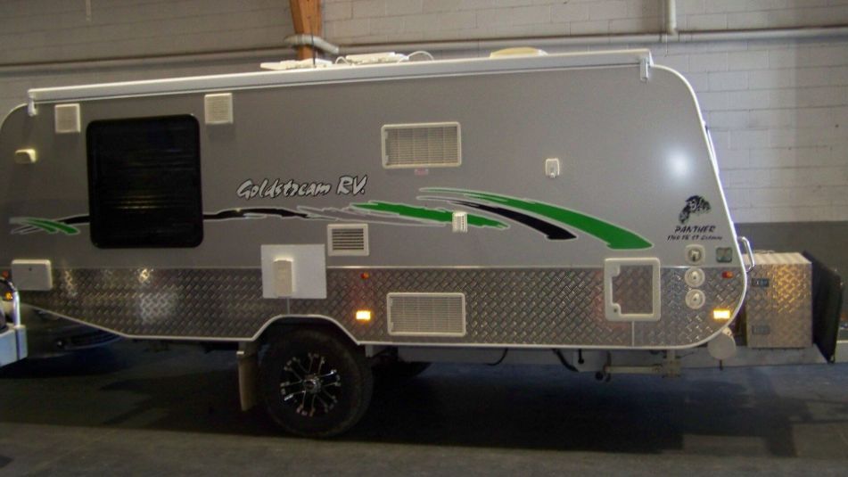 A Silver and Green Camper Trailer is Parked in a Garage — A Plus Automotive Electrical in Lavington, NSW