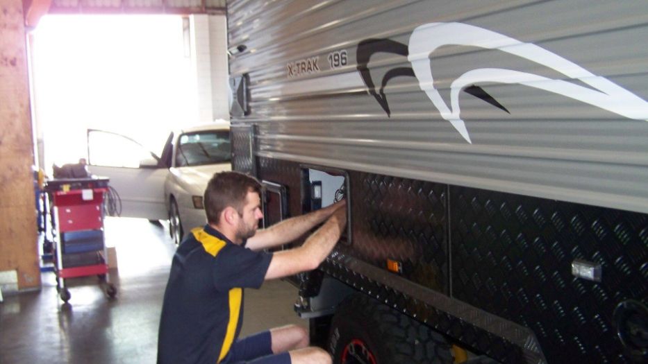 A Man is Working on a Camper in a Garage — A Plus Automotive Electrical in Lavington, NSW