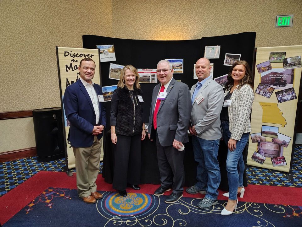 Five people stand in front of a display board. The board promotes Discover Mississippi. People smile.