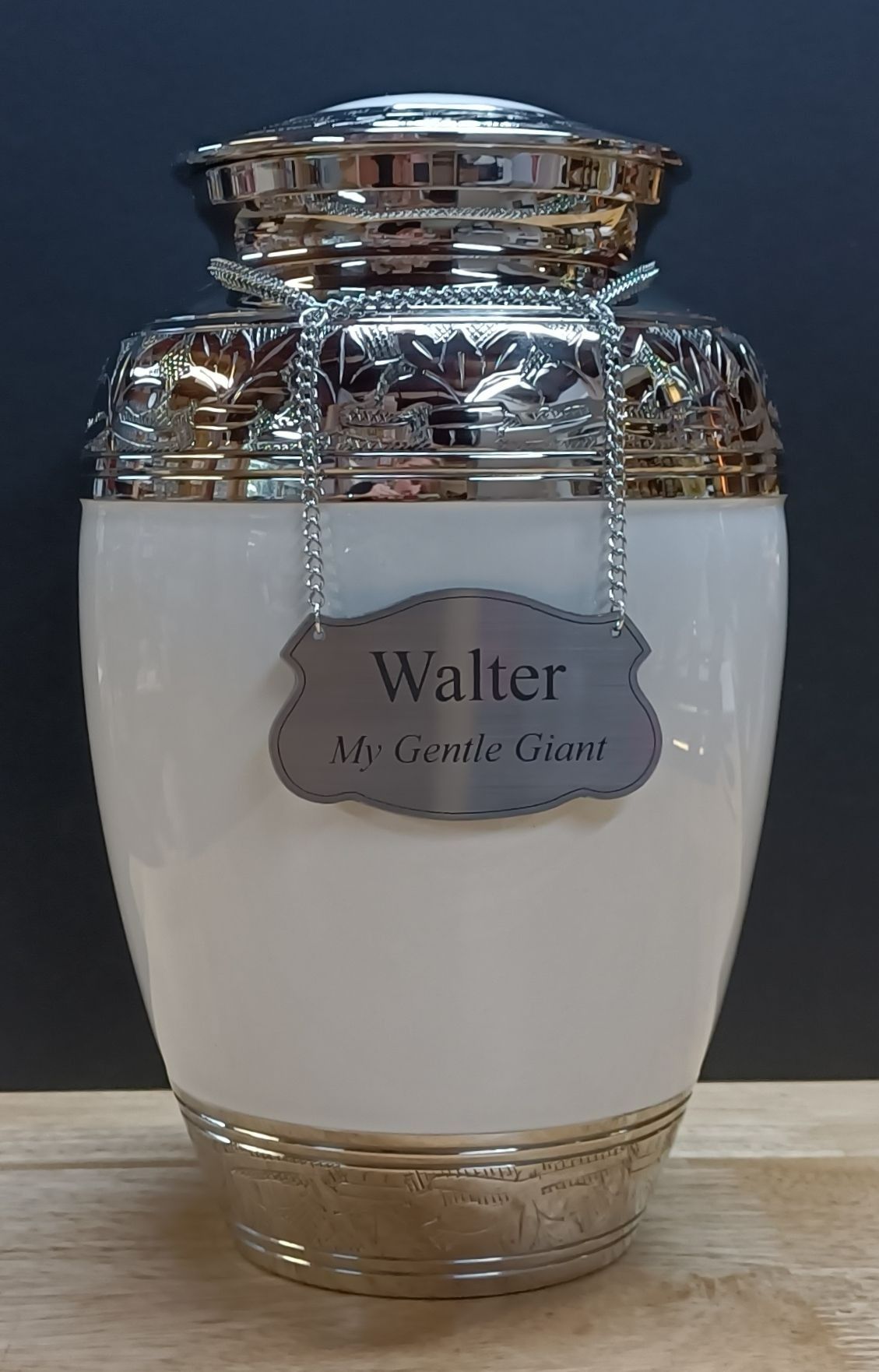 A White Urn With a Name Tag on It is Sitting on a Wooden Table — Pets Forever Cremations In North Lakes, QLD