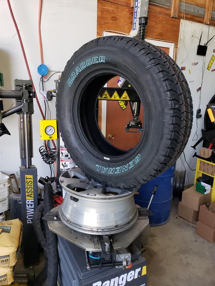 A tire is sitting on top of a tire changer in a garage.