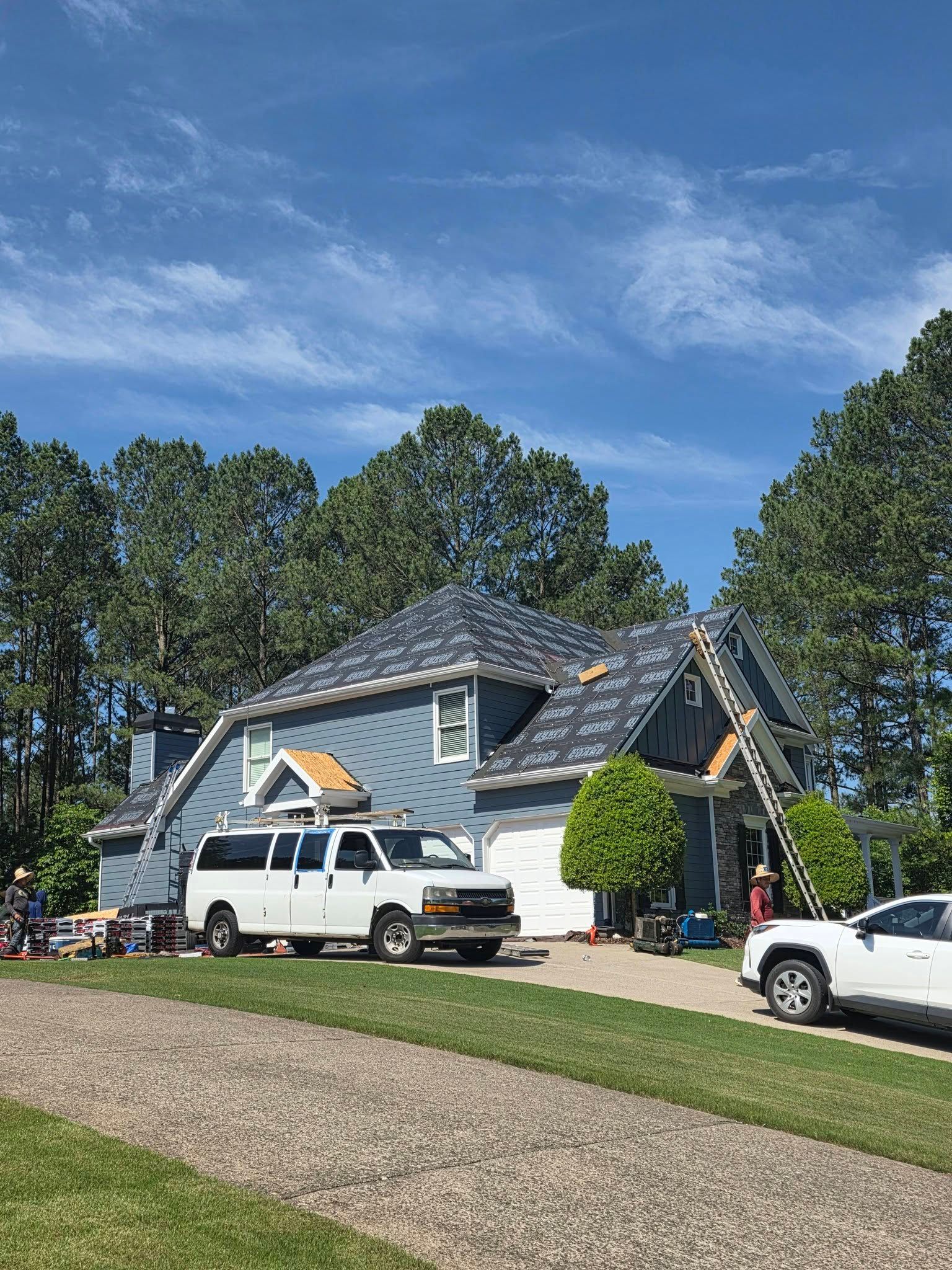 Suburban house with a white truck and SUV parked in the driveway under a blue sky