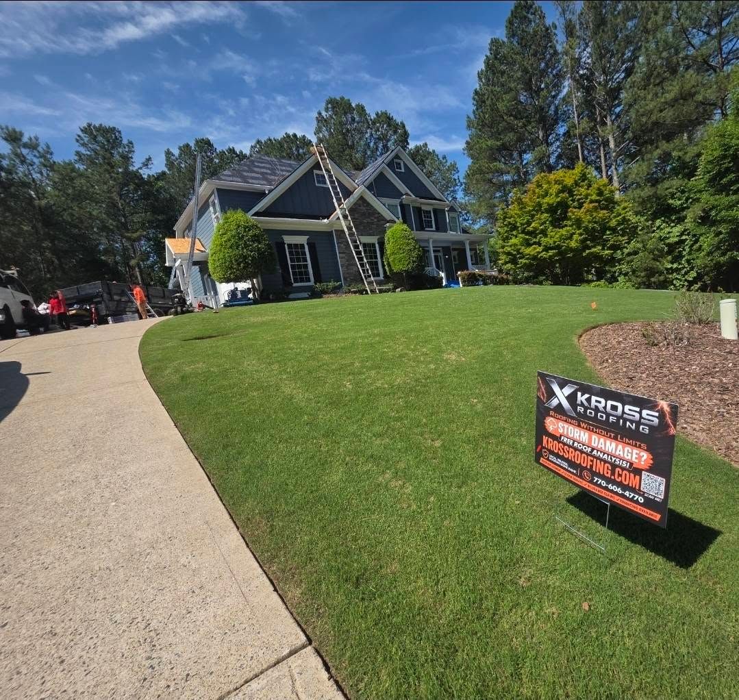 Large house with a gravel driveway and lawn, with a real estate sign in the foreground.