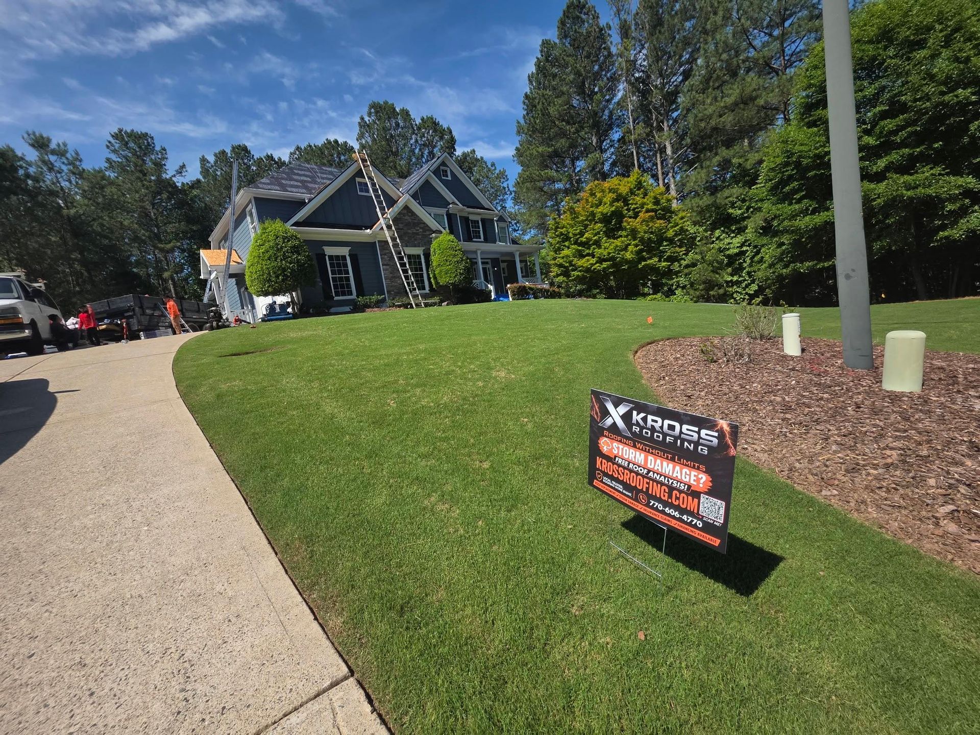 Suburban house with landscaped lawn and a real estate sign by the driveway on a sunny day