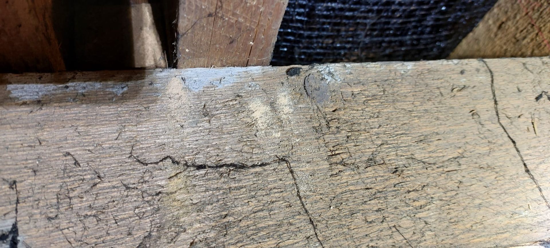 Close-up of a weathered, cracked wooden surface, possibly part of a building's structure.