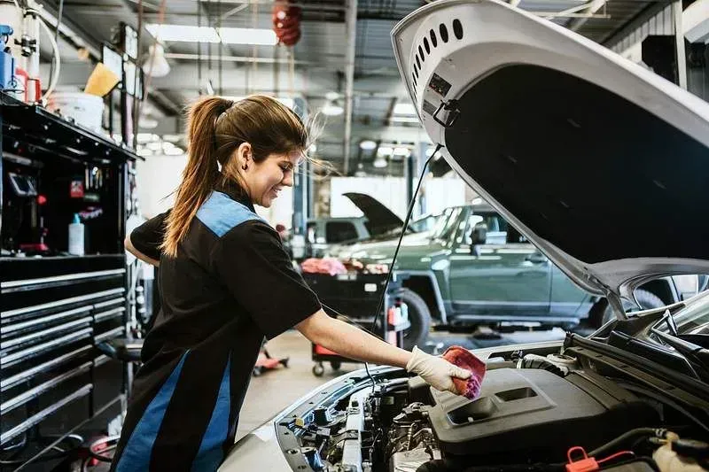 Female mechanic cleaning car engine.