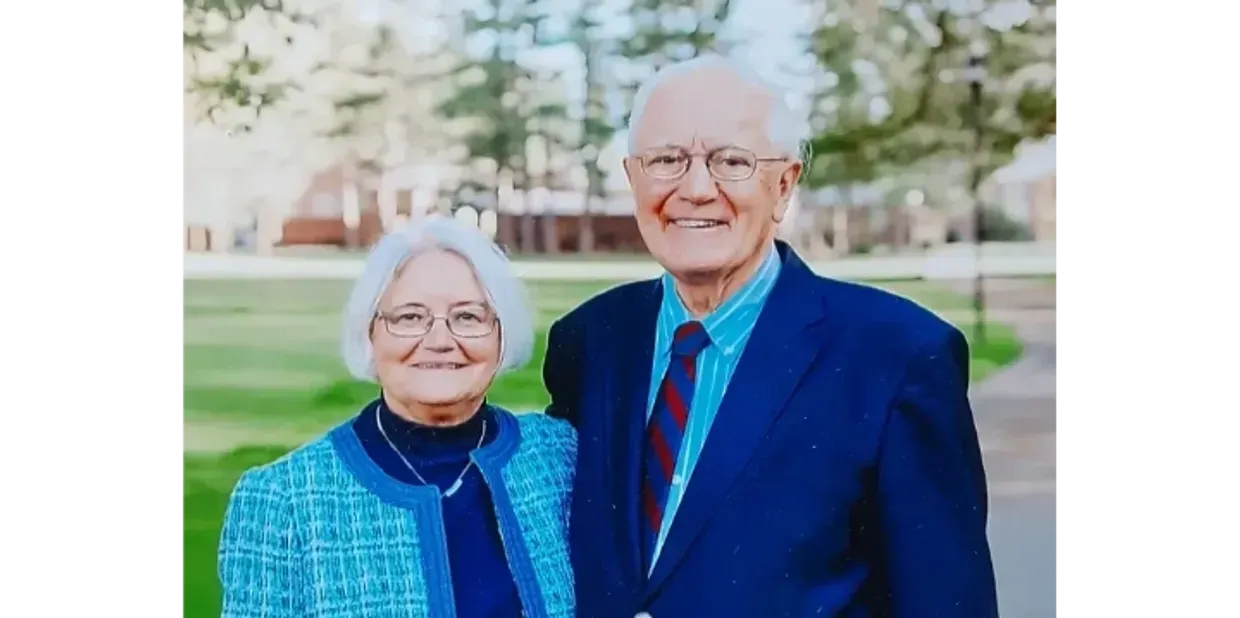 A man and a woman are posing for a picture in a park.