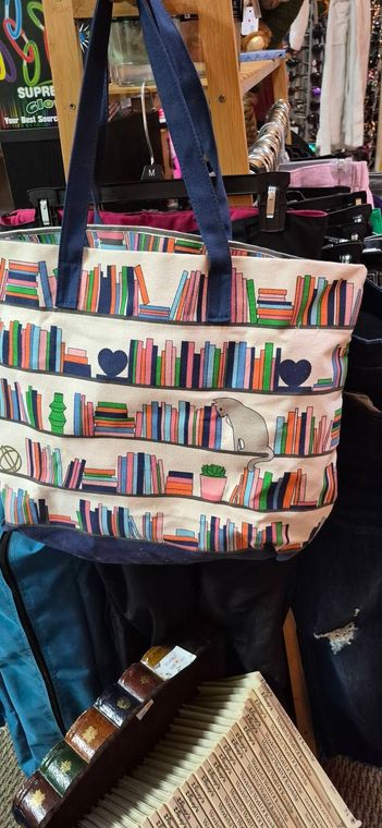 Canvas tote bag with colorful book spines design hanging in a shop display