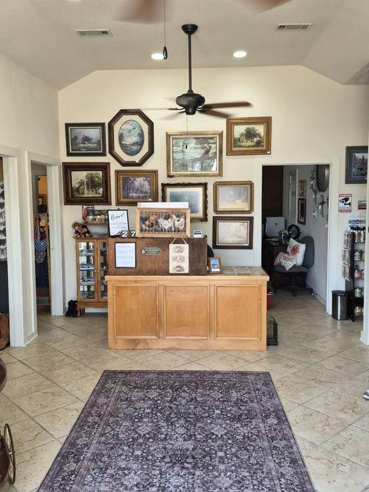 Lobby with wooden reception desk, framed artwork, tiled floor, and patterned rug under ceiling fan lights
