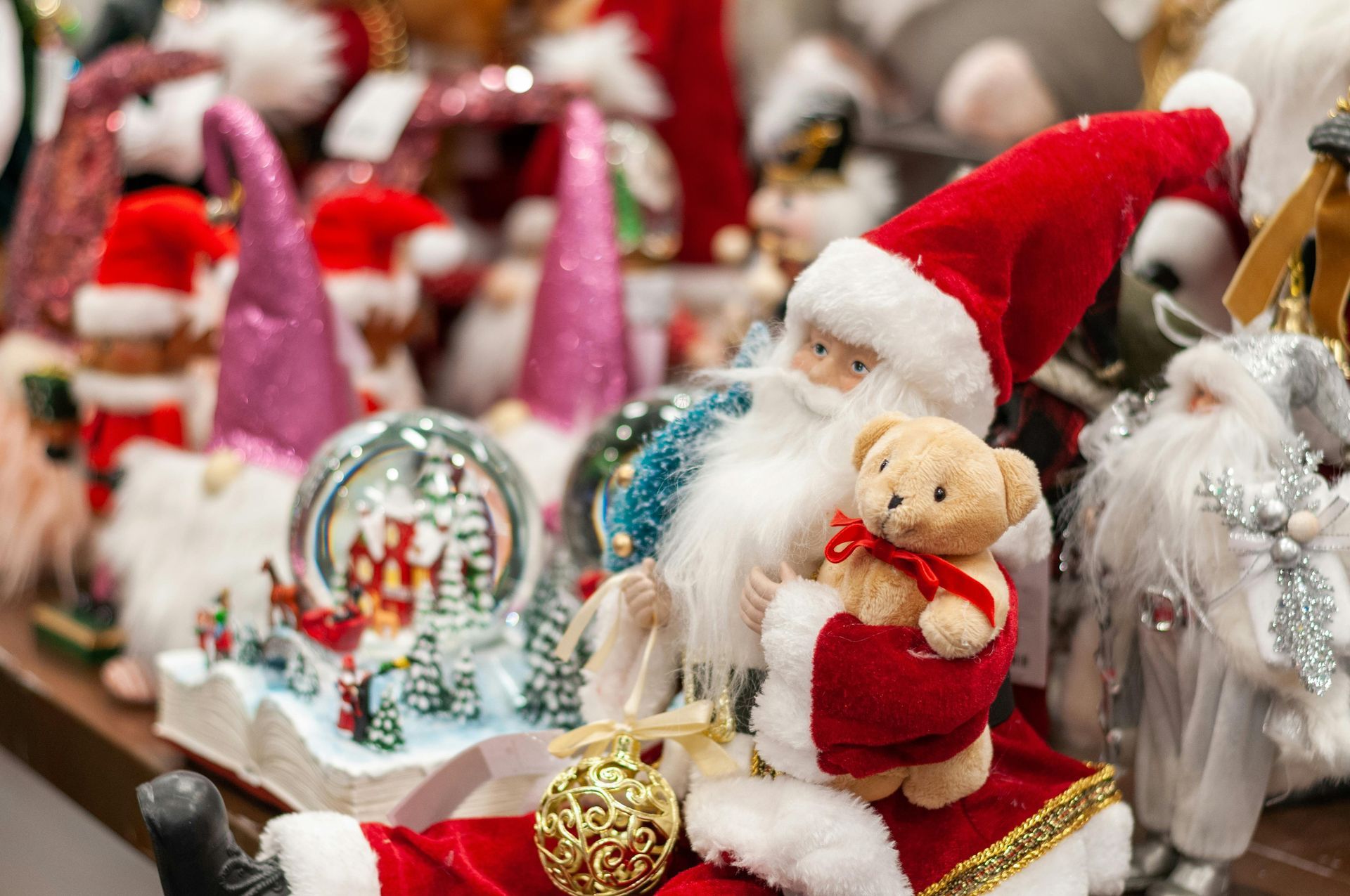 Santa figurines and holiday decorations with red, white, and gold accents on a festive display table