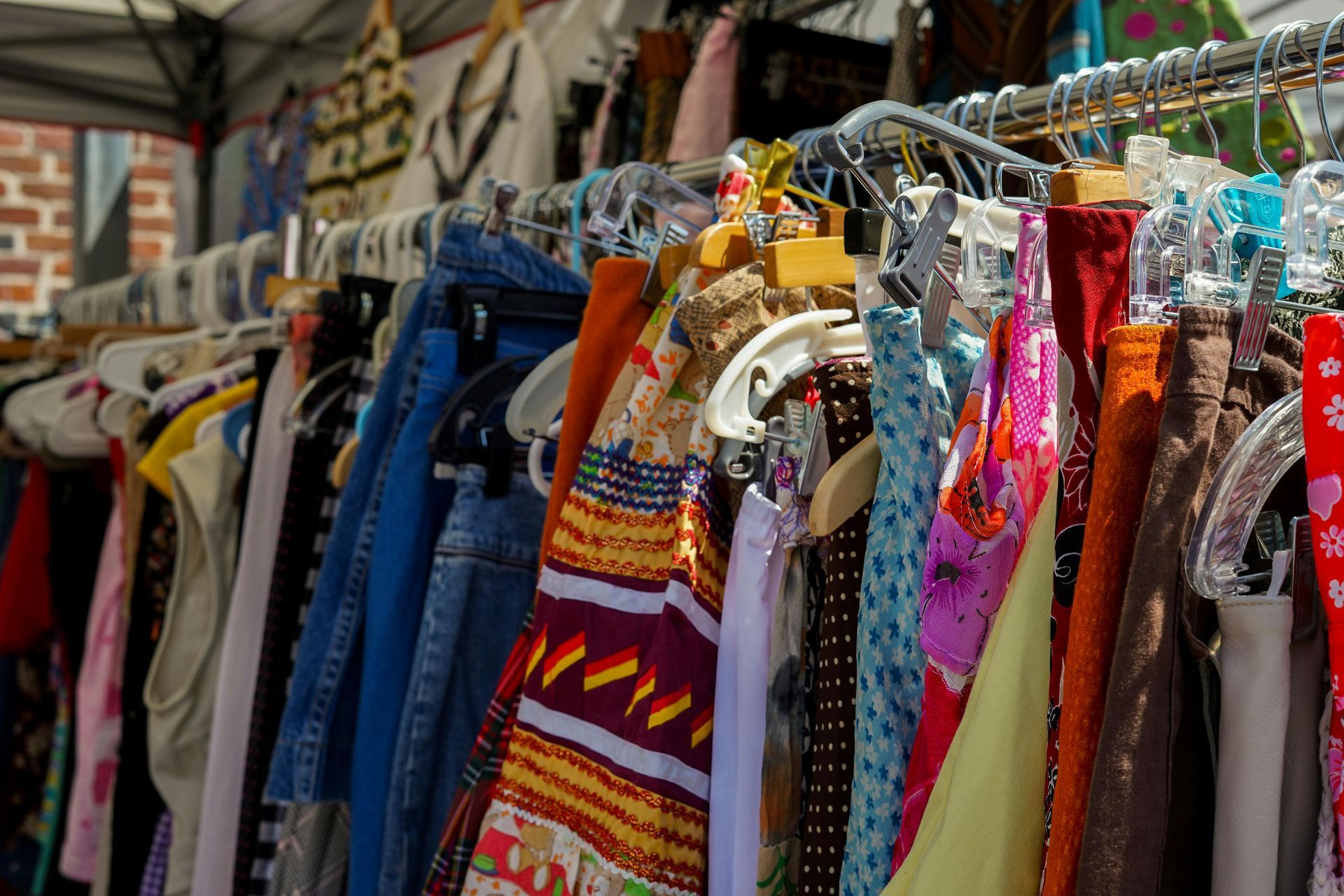 Racks of colorful clothes on hangers in a thrift store aisle