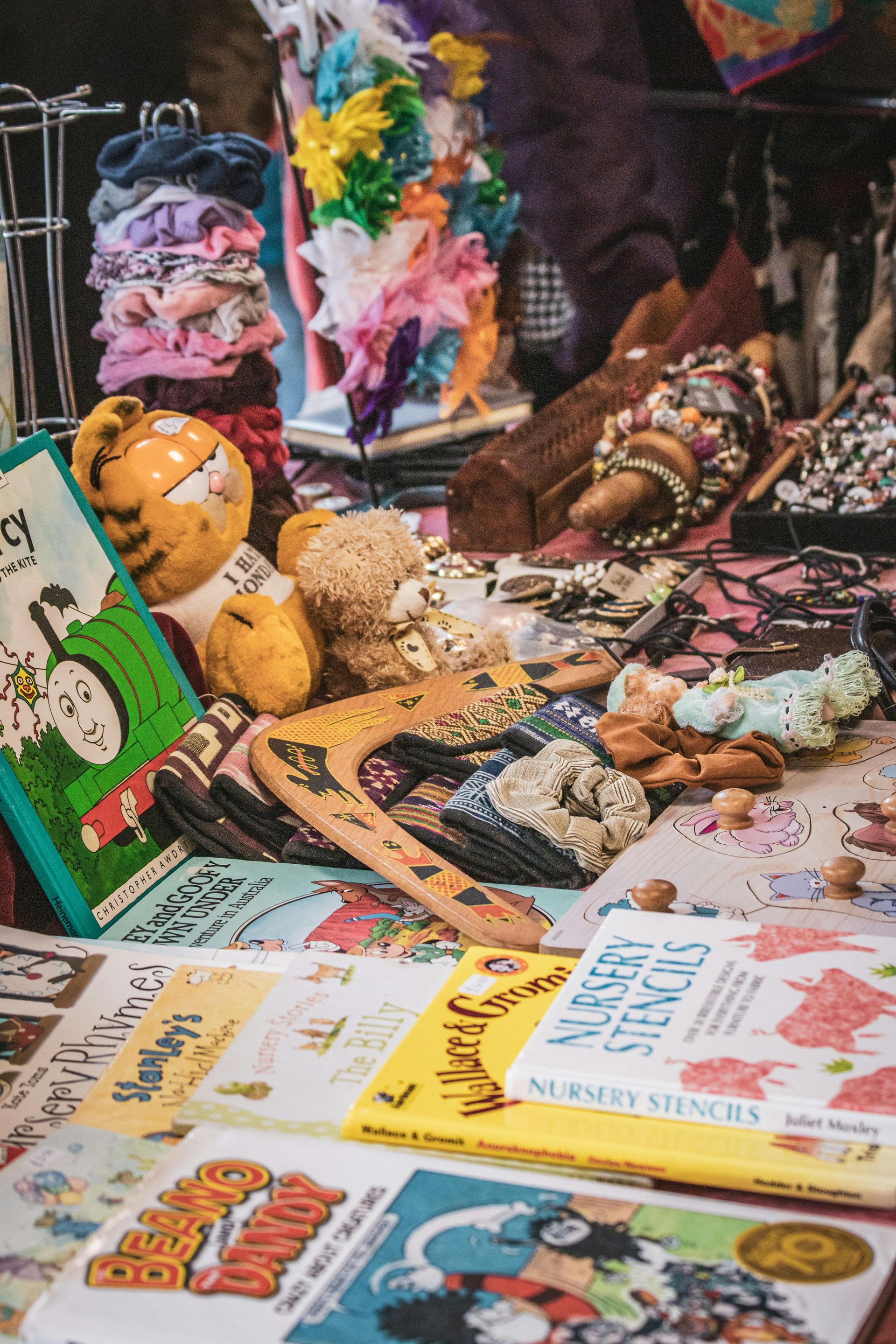 Assorted colorful jewelry and accessories displayed on a market table with handwritten signs
