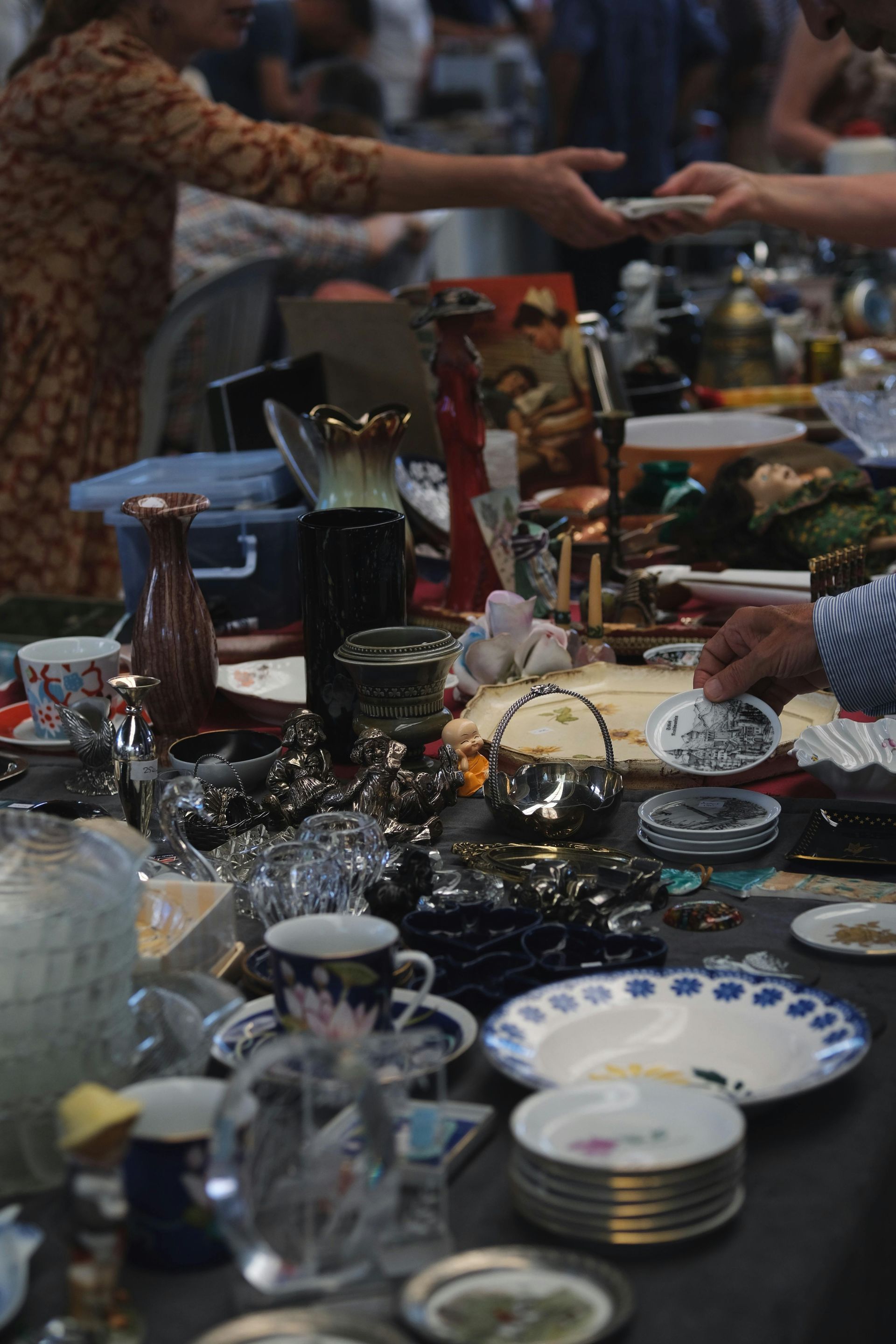 Crowded banquet table with dishes, glassware, and gifts as guests reach across it