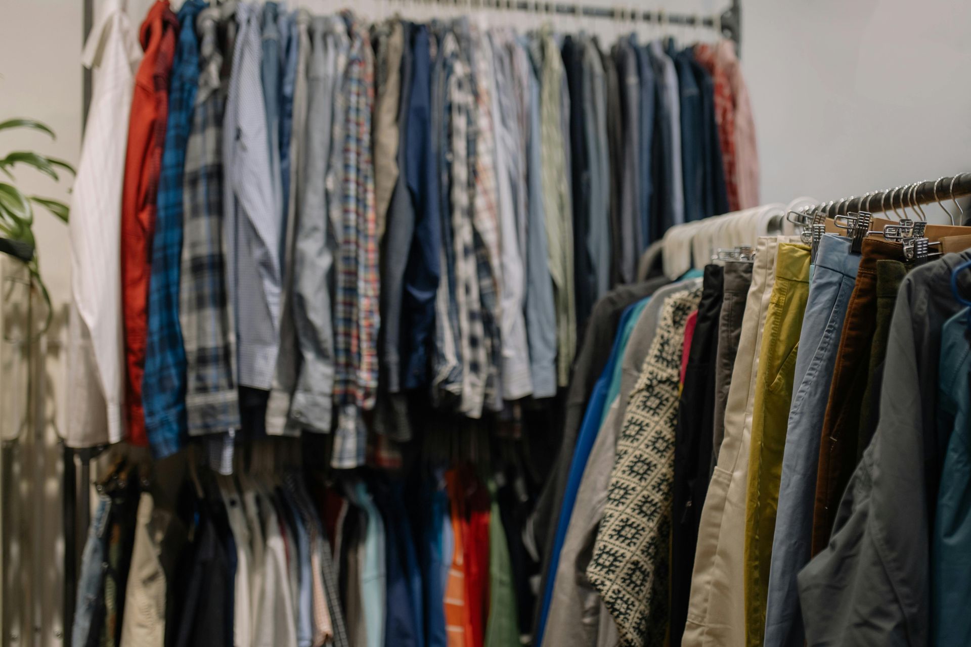 Clothes hanging on racks in a store, with shirts and jackets in assorted colors and patterns