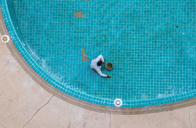 Person wading in a blue tiled swimming pool beside the curved edge