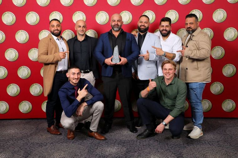 a group of men are posing for a picture and one of them is holding a trophy .