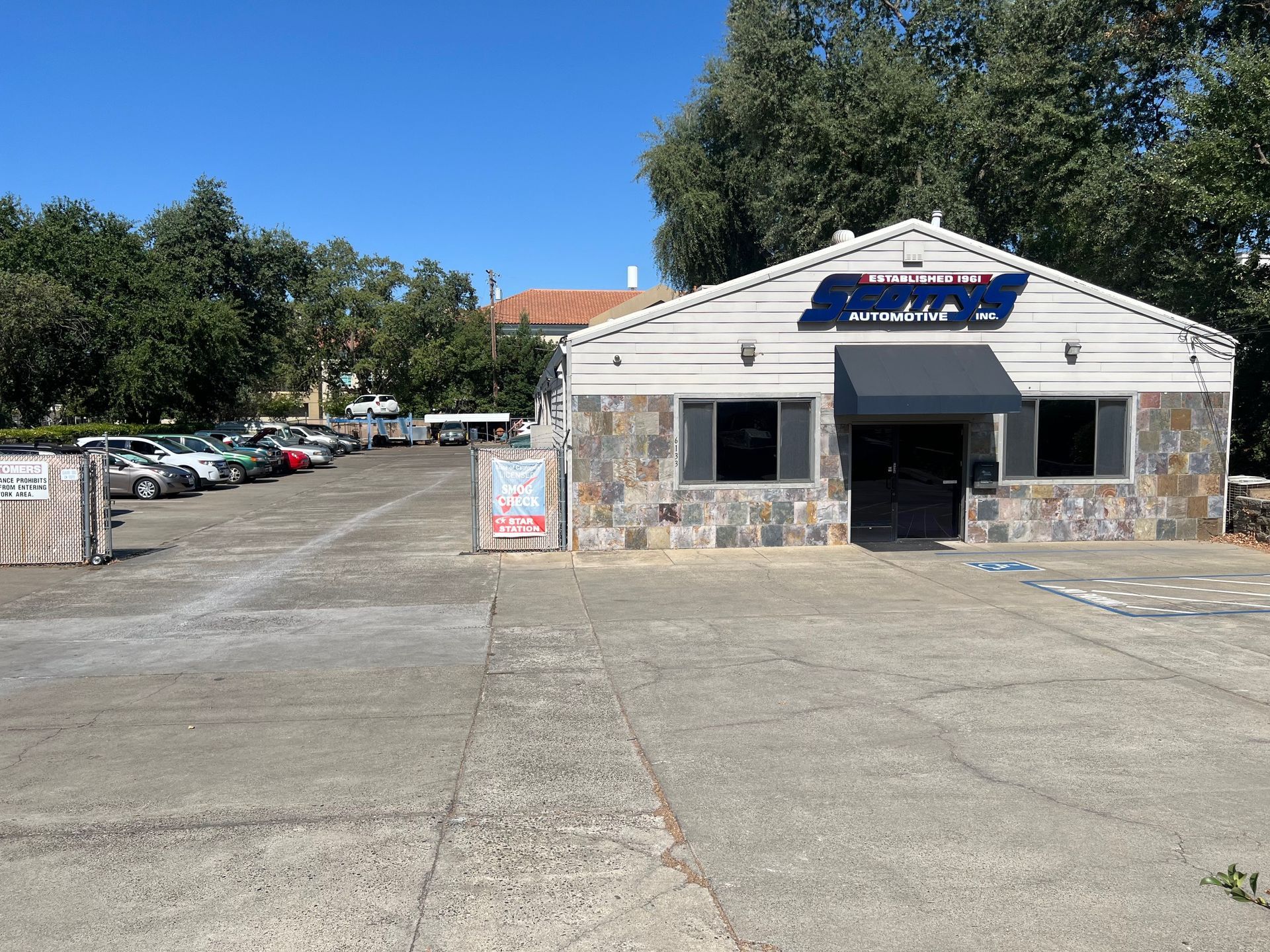Small roadside convenience store with stone facade and empty parking lot under a clear blue sky