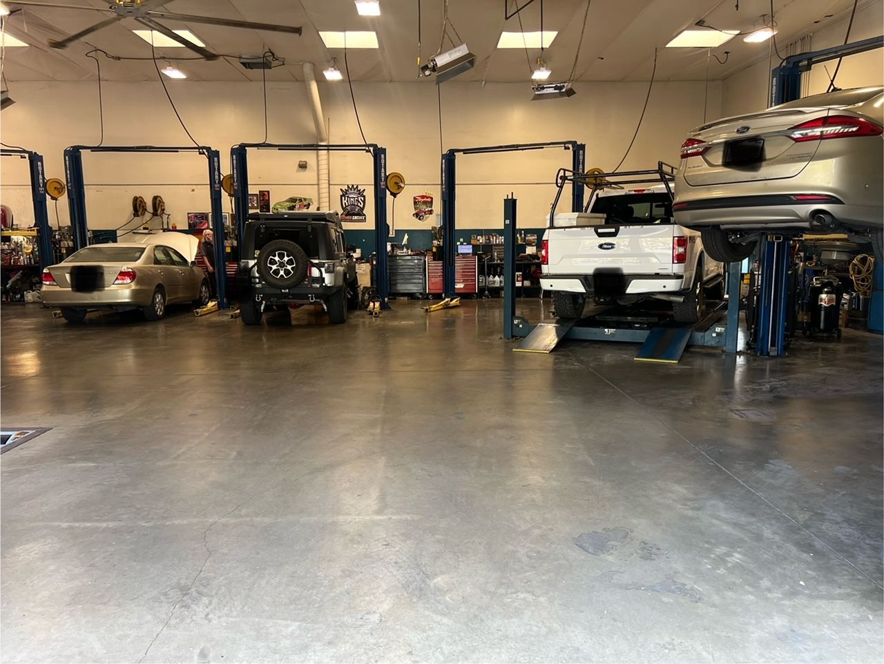Auto repair shop with several cars on lifts and a vehicle being worked on inside the garage