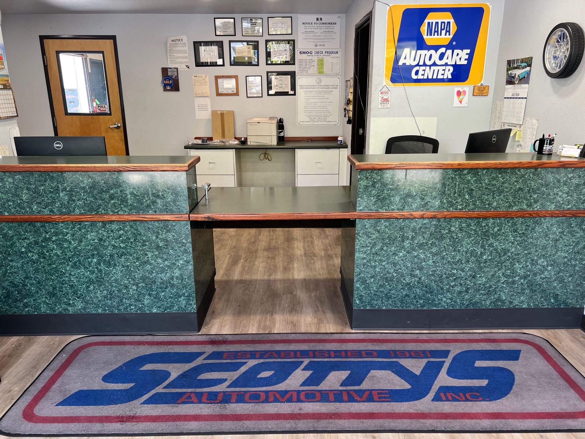 AutoZone store counter with teal walls, service desk, and branded floor mat, with a rear waiting area behind it