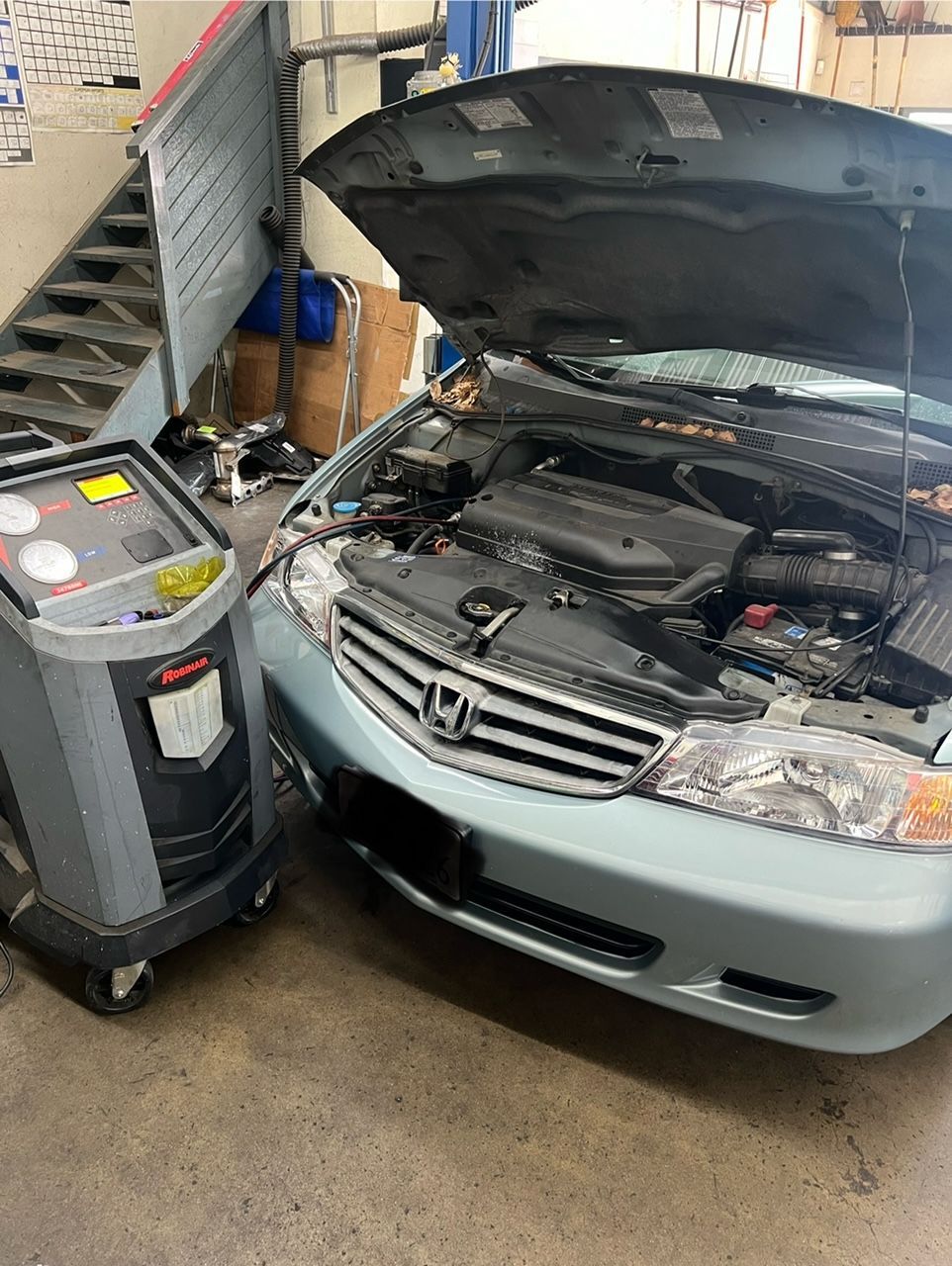 Silver Honda sedan with hood open in an auto shop beside a diagnostic machine