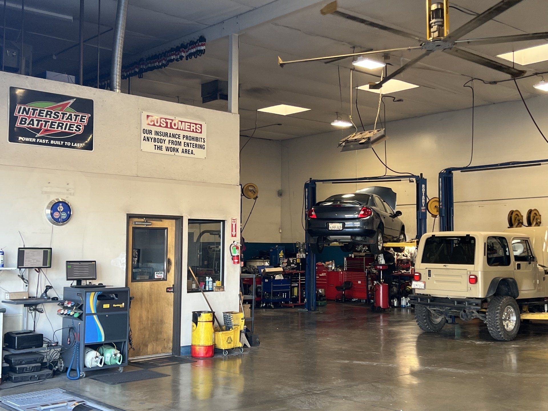 Auto repair shop with a car on a lift, a Jeep, tools, and equipment inside a garage