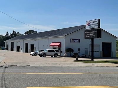 Wilson's Automotive building with a sign and two cars parked outside on a sunny day. |  Johnson's Automotive
