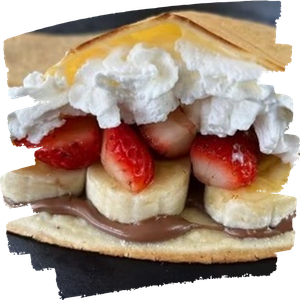 Crepe with chocolate spread, banana slices, strawberries, and whipped cream topping