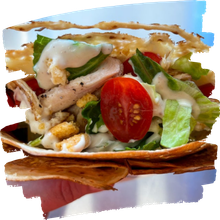 Grilled chicken salad in a crispy tortilla bowl with lettuce, cherry tomato, and creamy dressing.