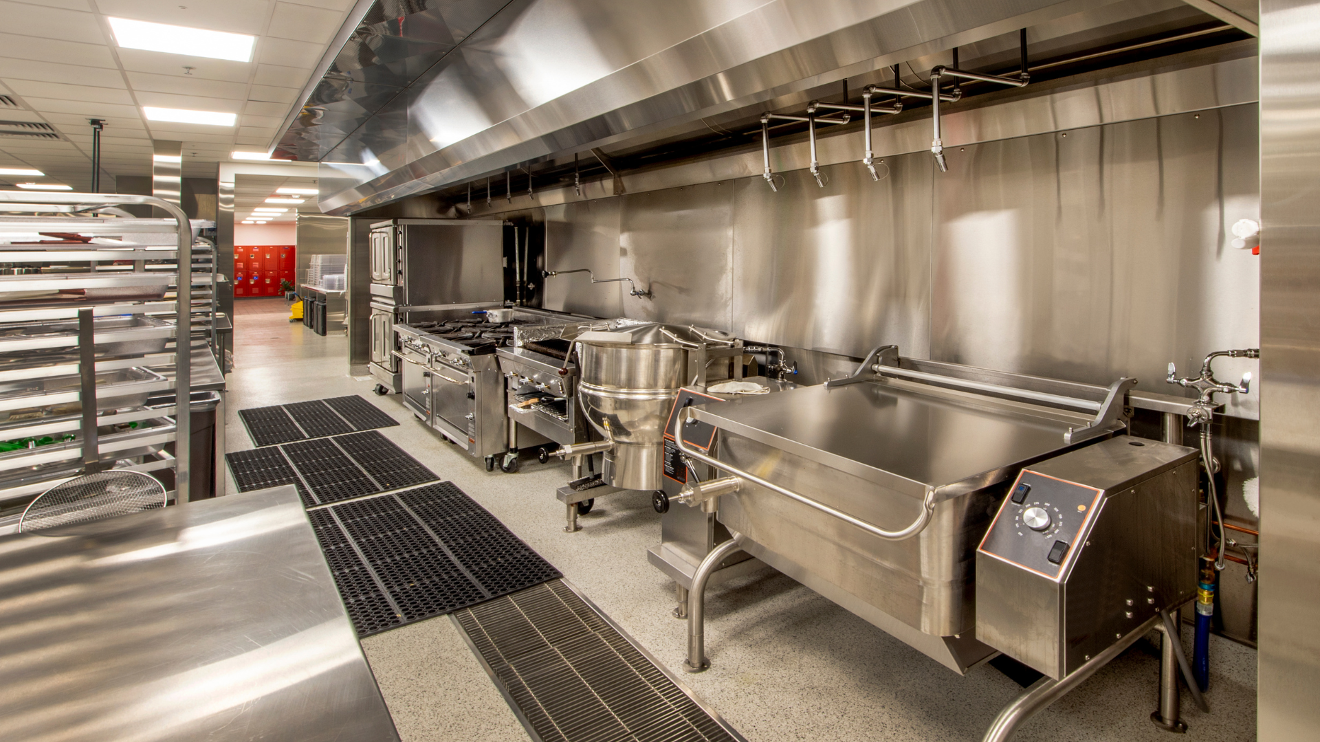 Industrial kitchen under construction with stainless steel appliances and a worker installing equipment