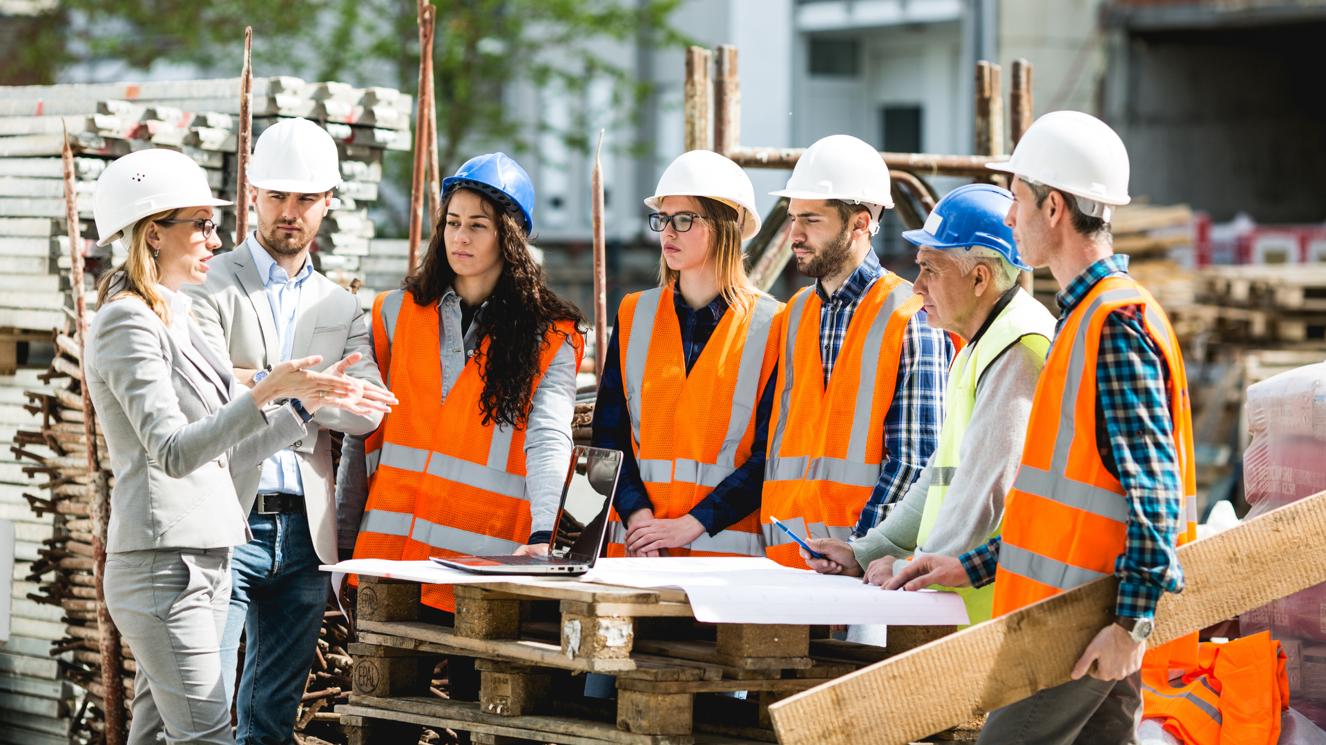 Construction team in hard hats and orange safety vests reviewing plans at a job site