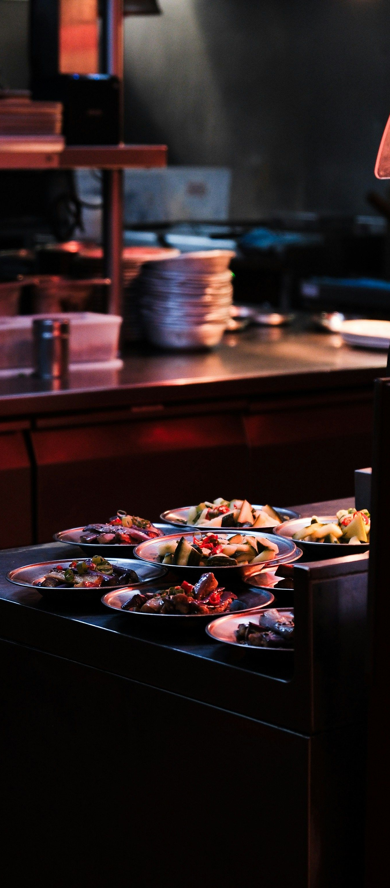 Dim restaurant counter with colorful pastries on a tray under warm lighting.