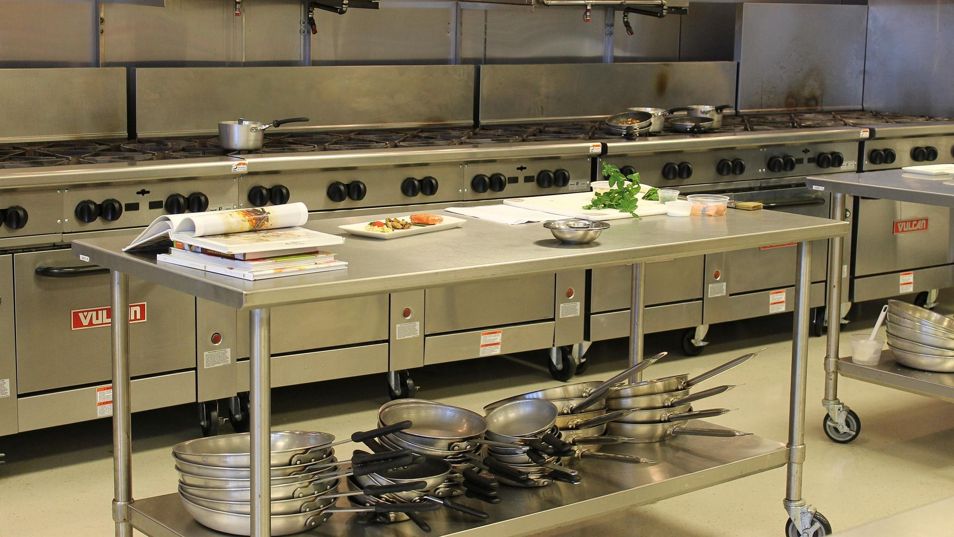Commercial kitchen with stainless steel appliances and food preparation area.