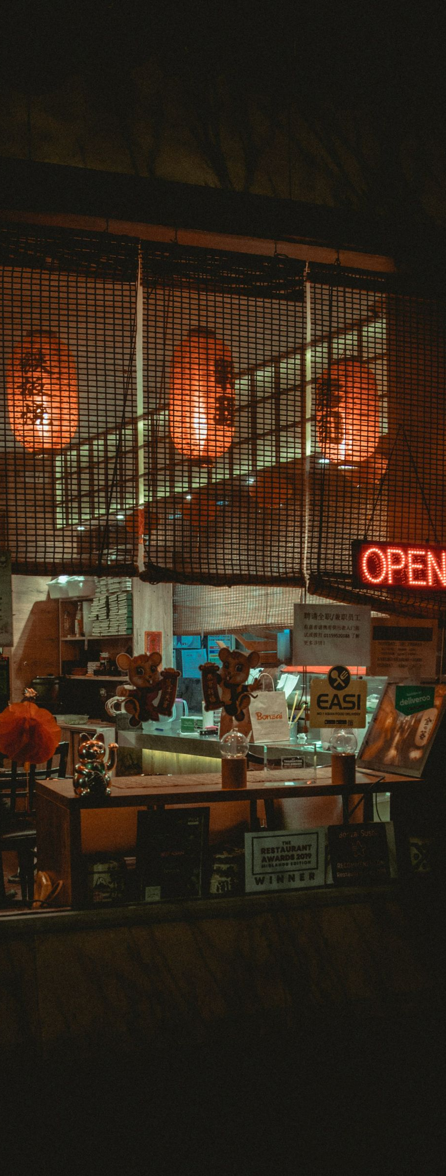 Dimly lit café at night with warm orange lights and a red neon “OPEN” sign.