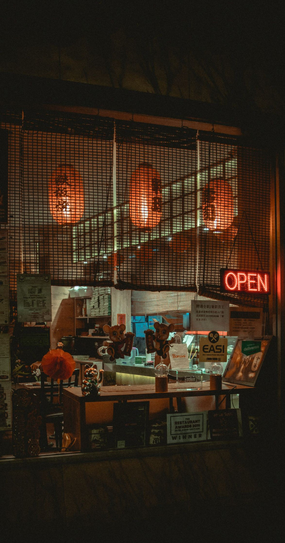 Dimly lit café at night with warm orange lights and a red neon “OPEN” sign.
