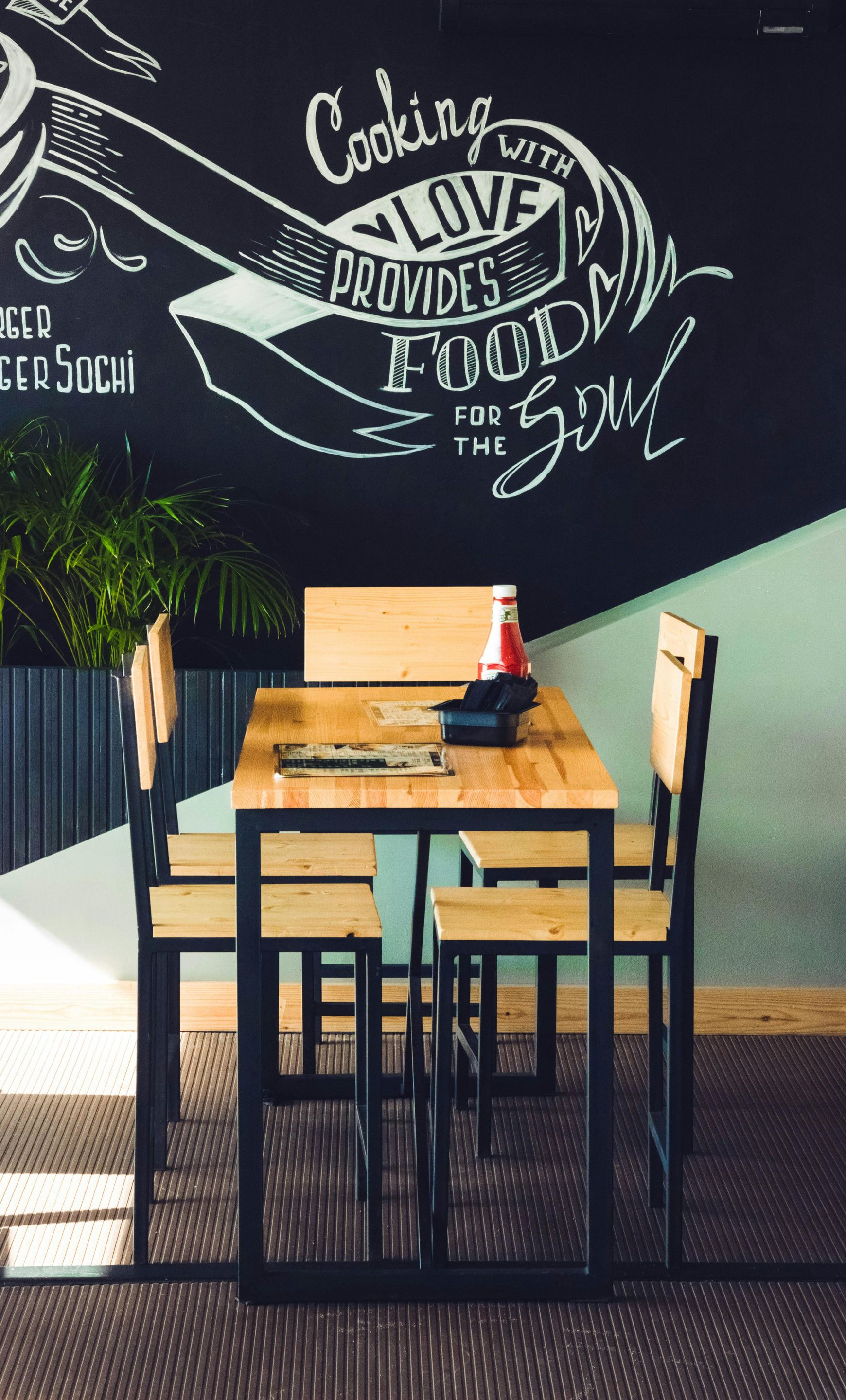 Restaurant dining table with four chairs against a chalkboard wall.