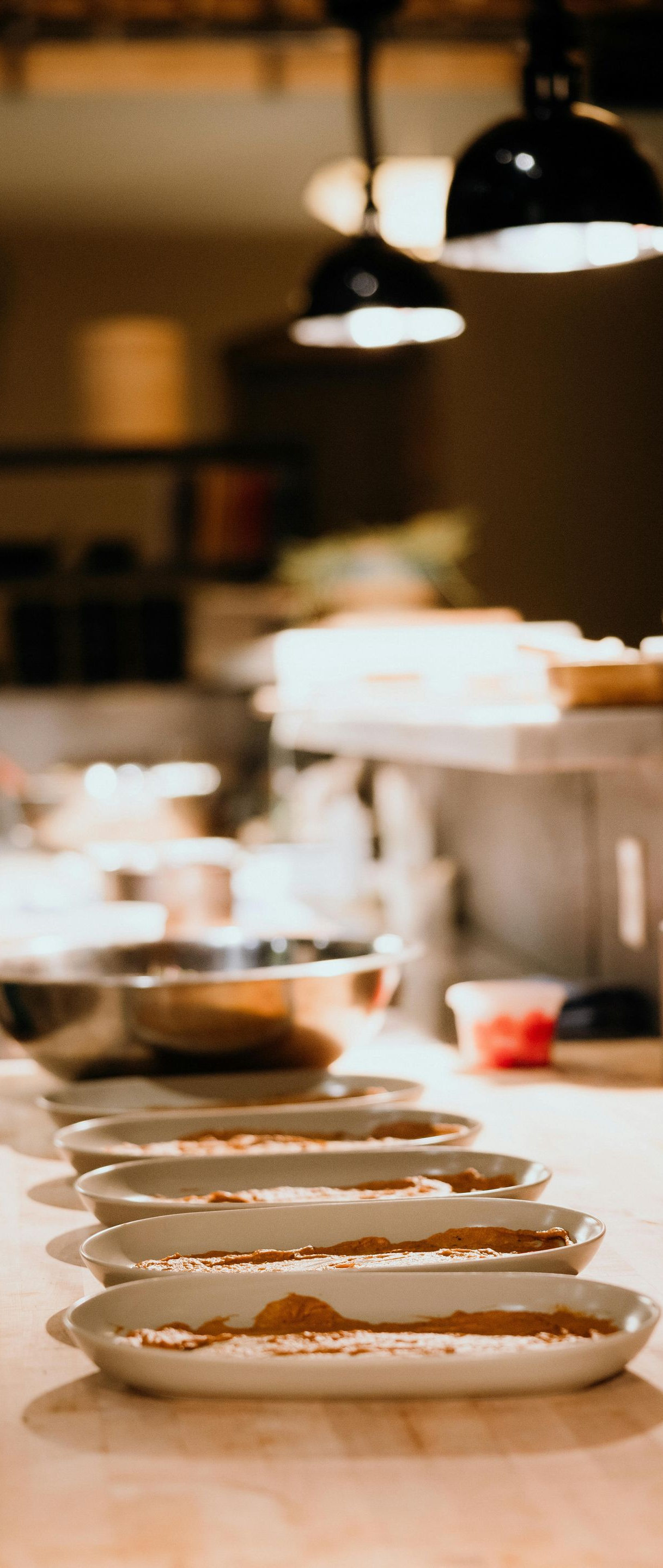 Row of plated dishes on a kitchen counter under warm hanging lights
