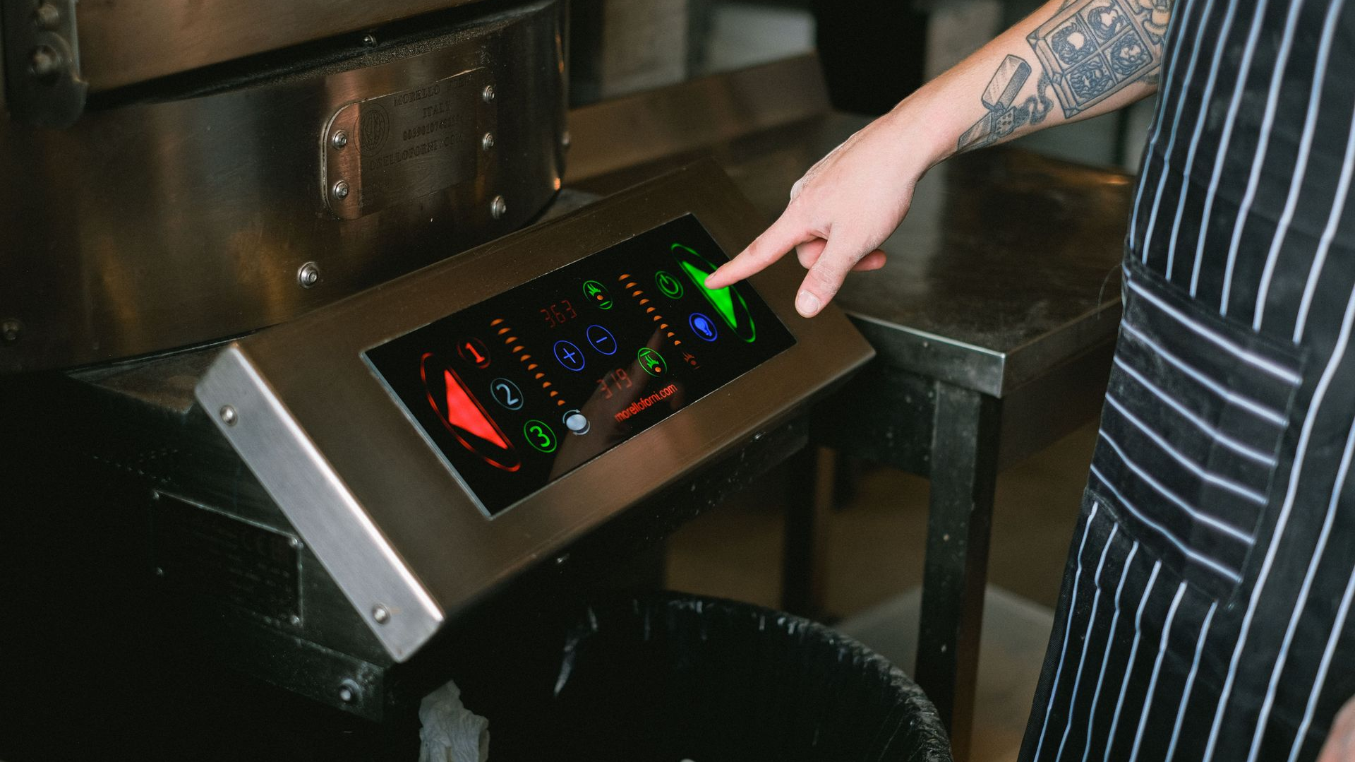 Person pointing at a colorful touchscreen control panel in an industrial setting