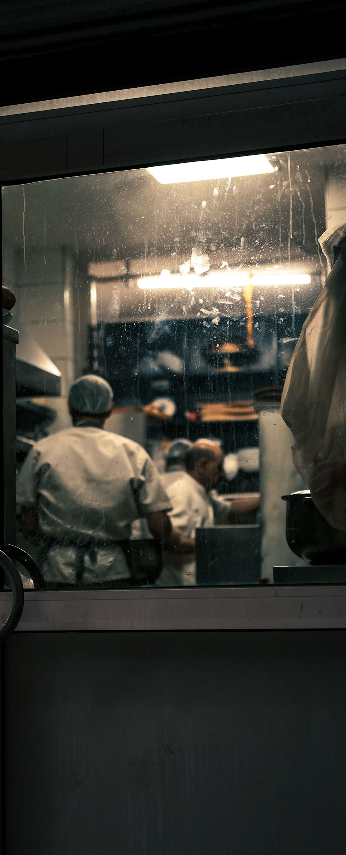 Two helmeted workers sit inside a dimly lit industrial vehicle or machine cabin.