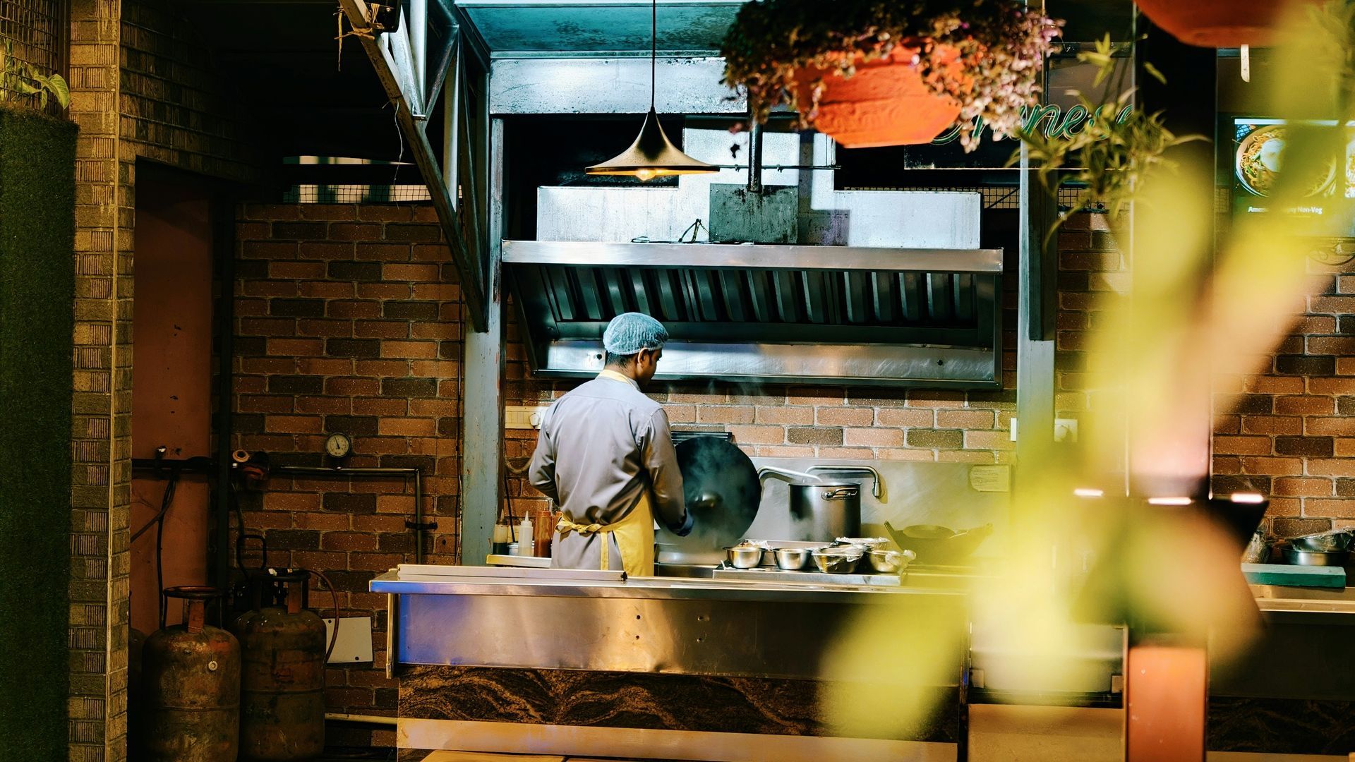 Chef plating food at a warmly lit restaurant kitchen counter