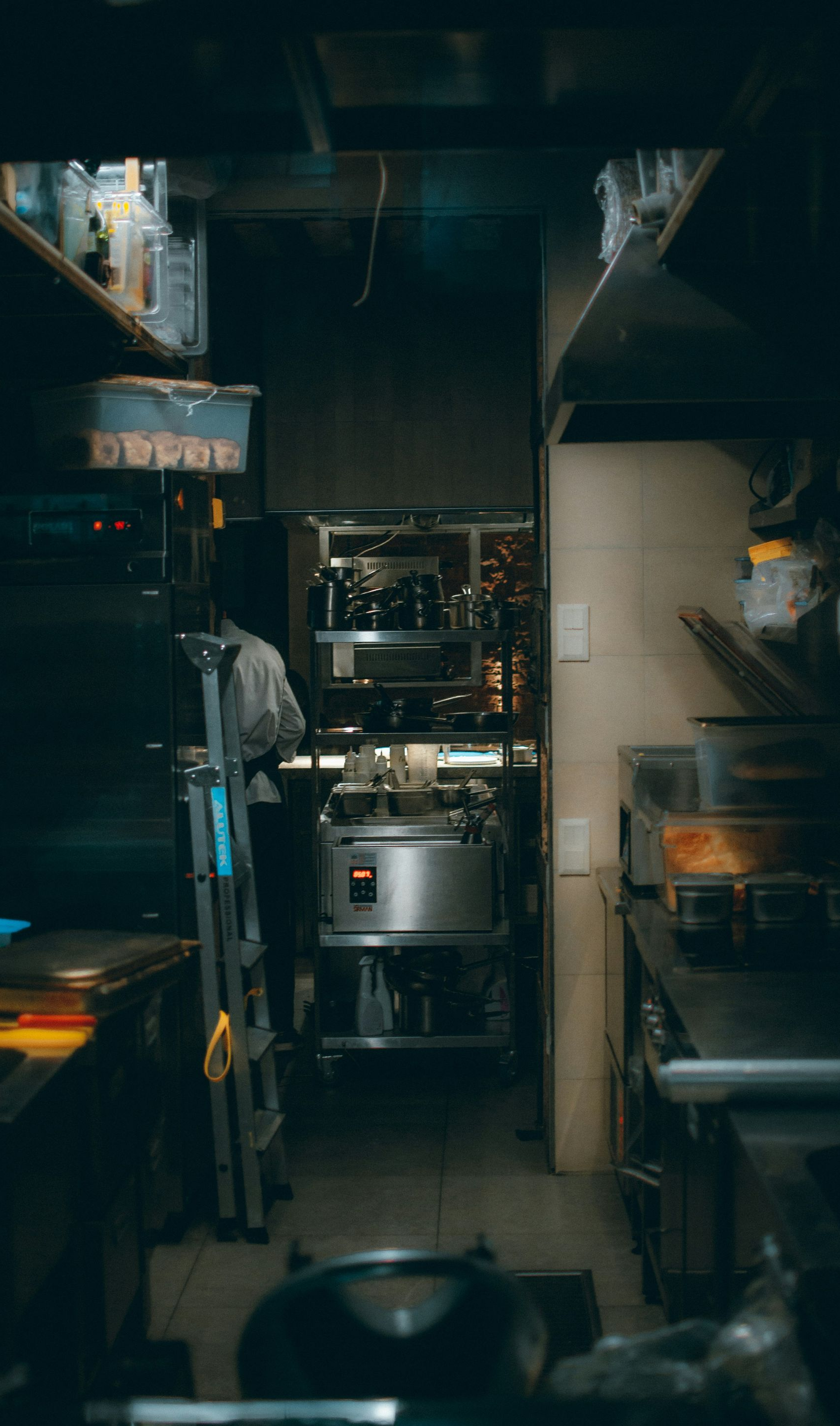 Restaurant kitchen with stainless steel equipment and a person standing by a machine.