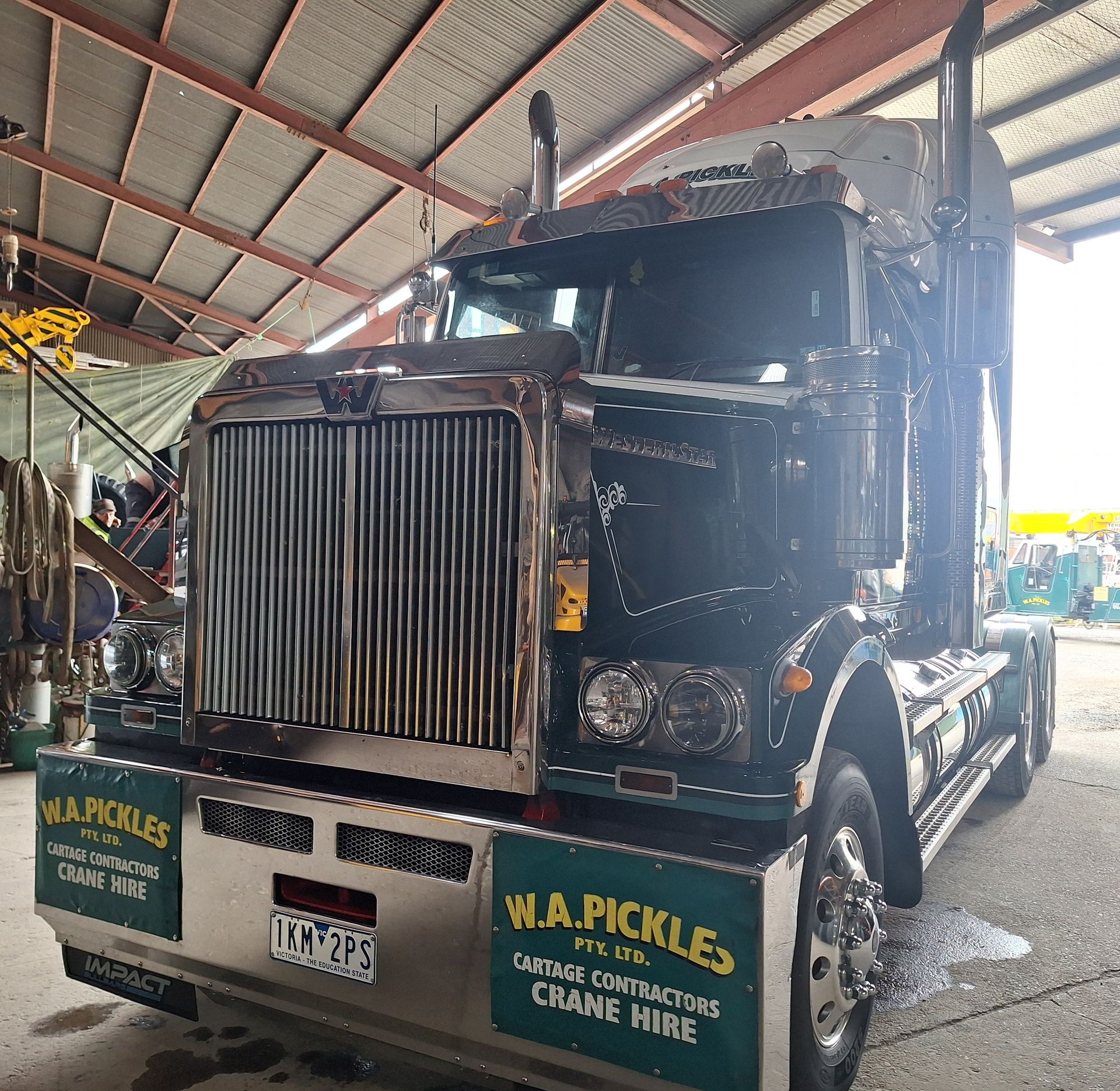 Black semi-truck parked indoors, front view with chrome grille and W.A. Pickles signage on the bumper.
