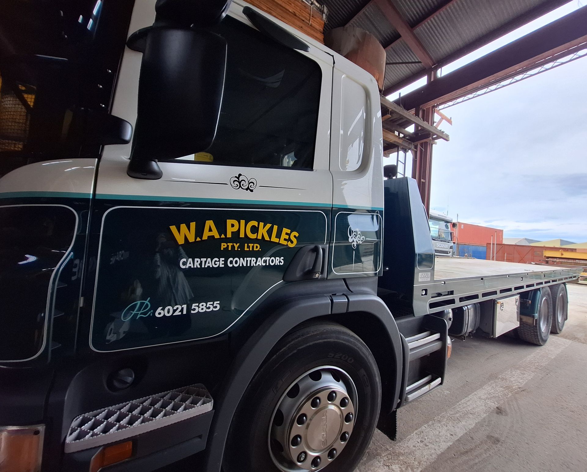 Black W.A. Pickles flatbed truck parked under a covered loading dock