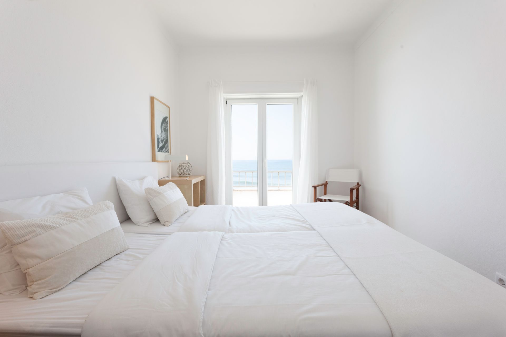 a bedroom with two beds , a chair and a large window .