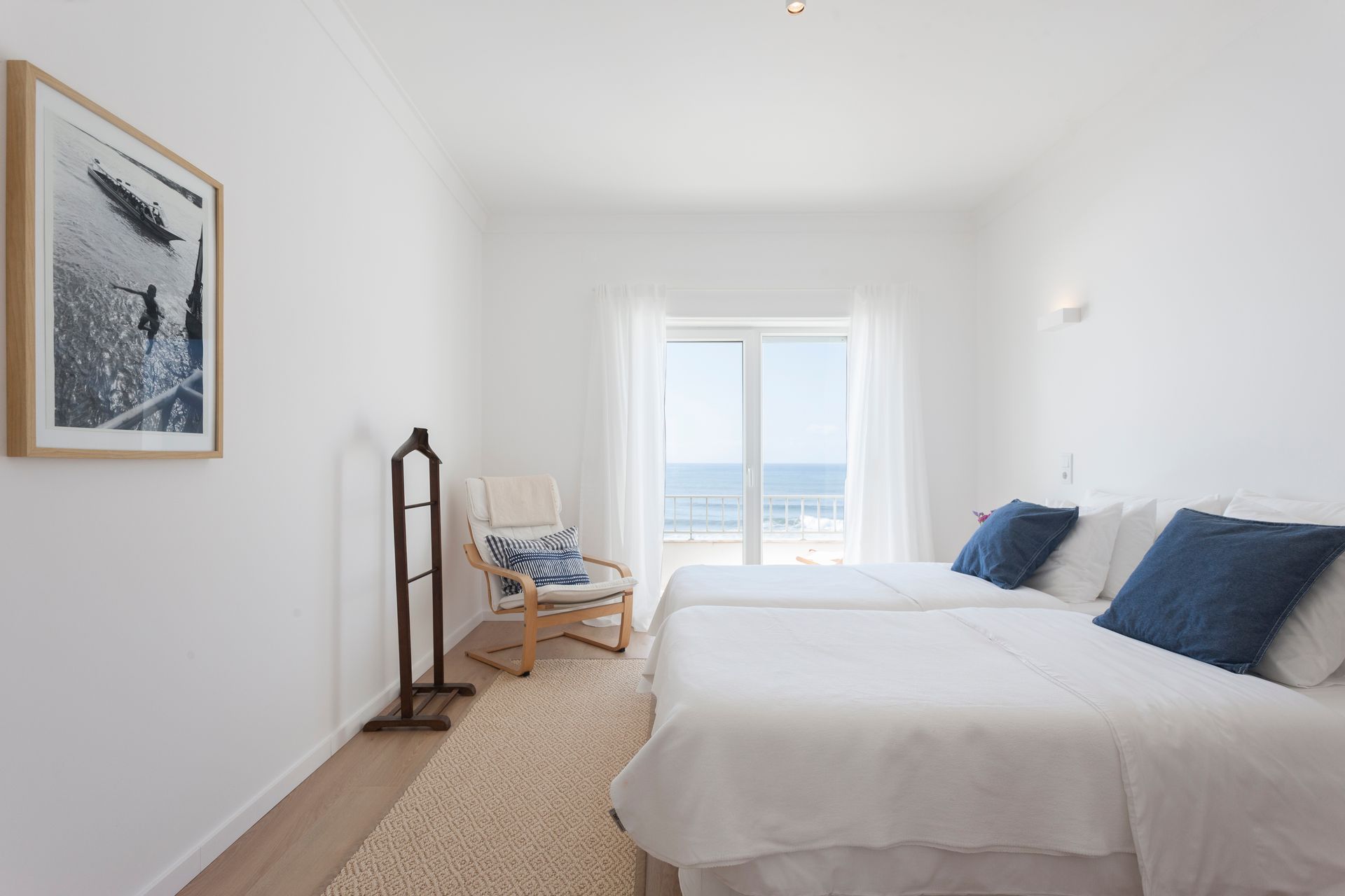 a bedroom with two beds , a chair and a picture on the wall .
