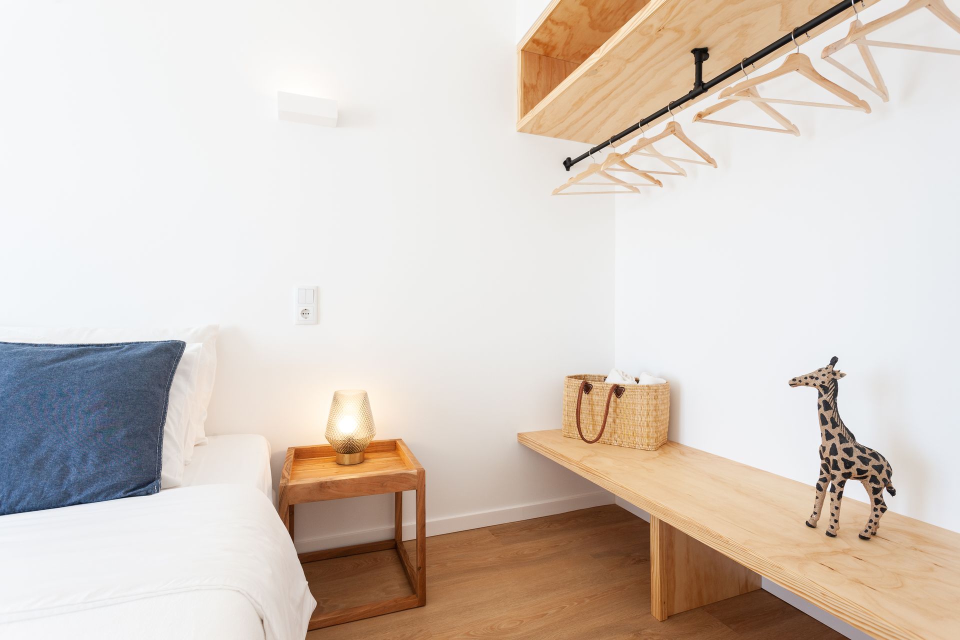 a bedroom with a bed , nightstand , table and a giraffe figurine .