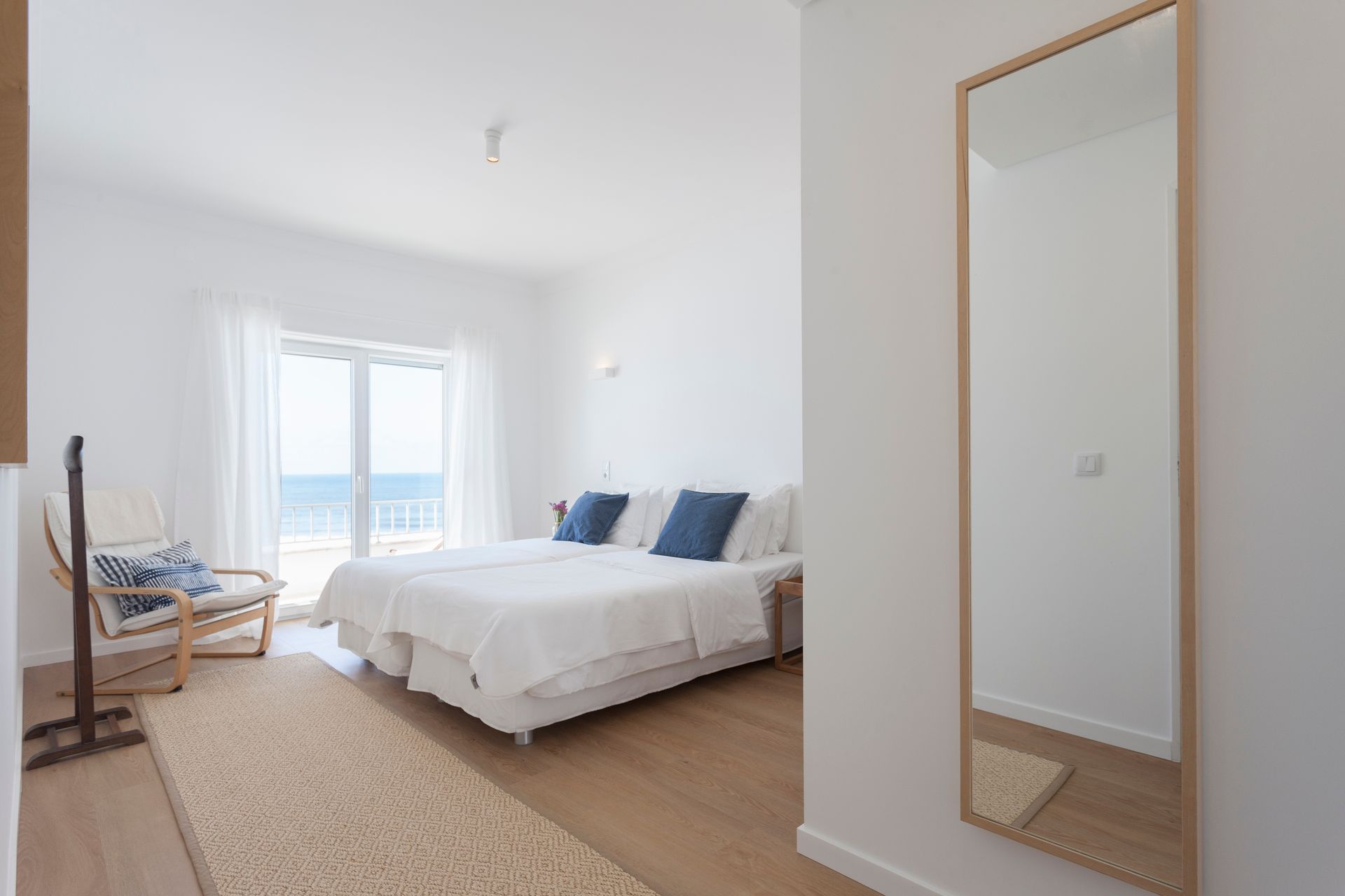 a bedroom with two beds , a chair and a large mirror .