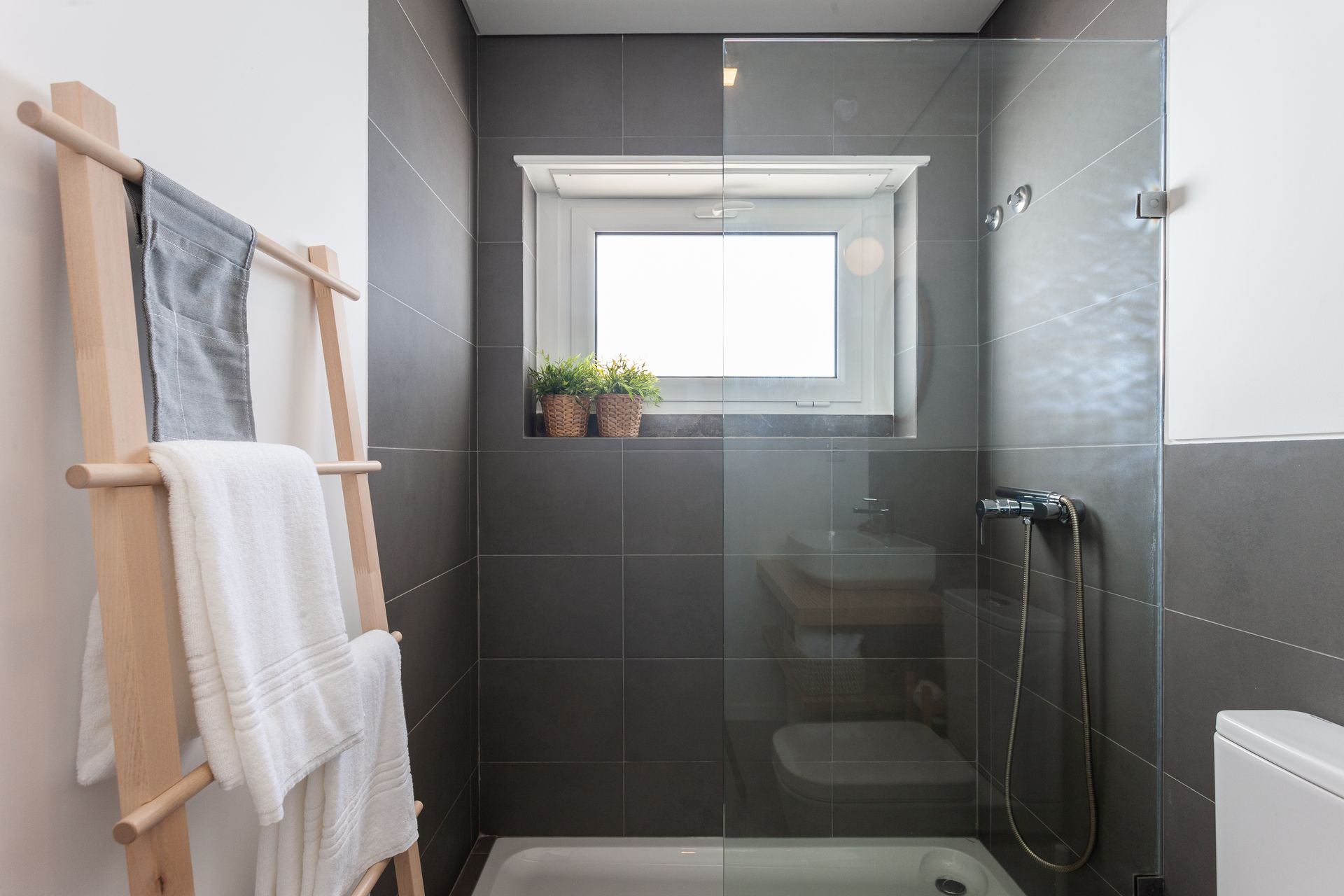 a bathroom with a walk in shower , sink , toilet and window .