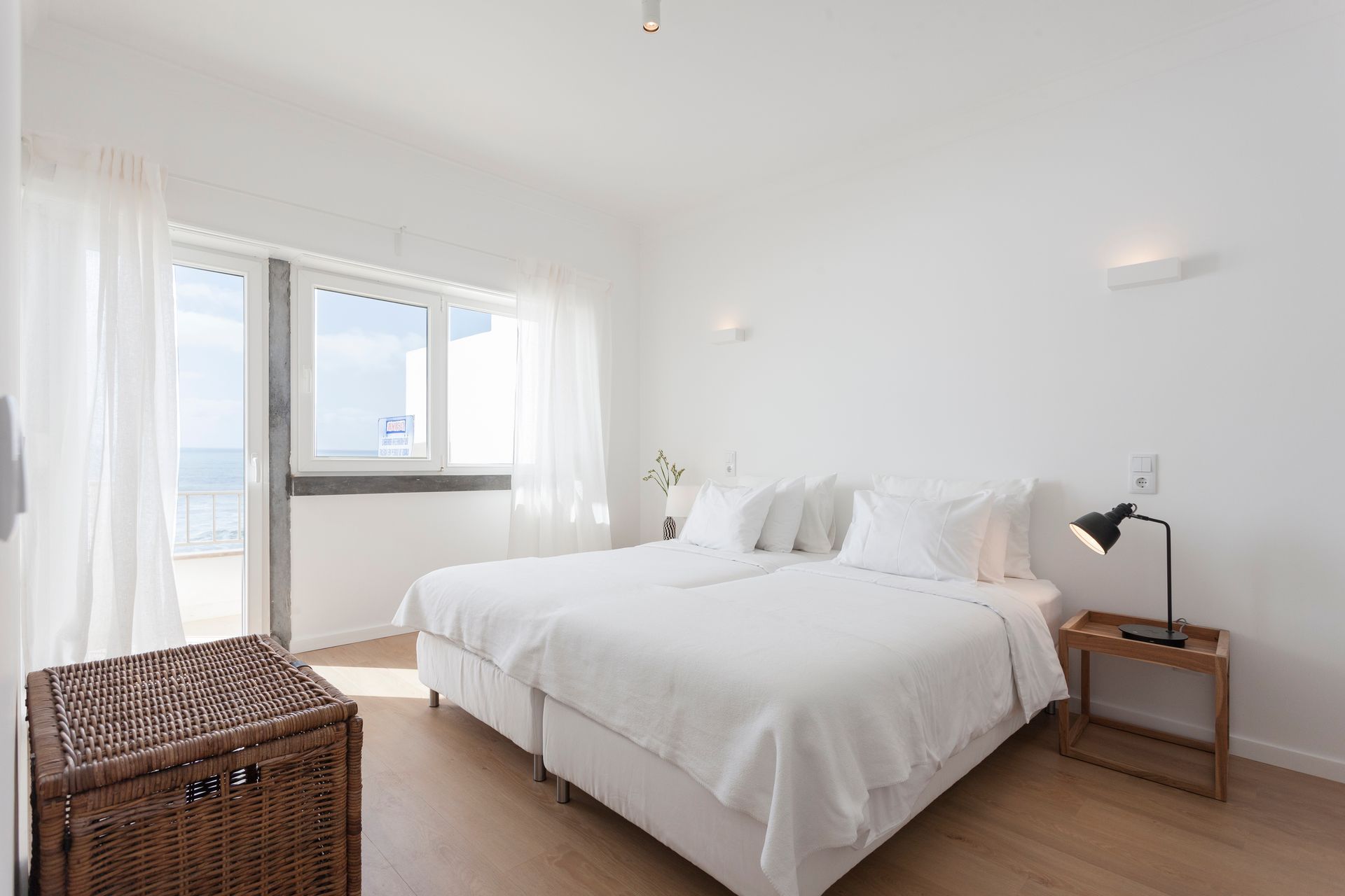 a bedroom with two beds , a trunk , a lamp and a window .
