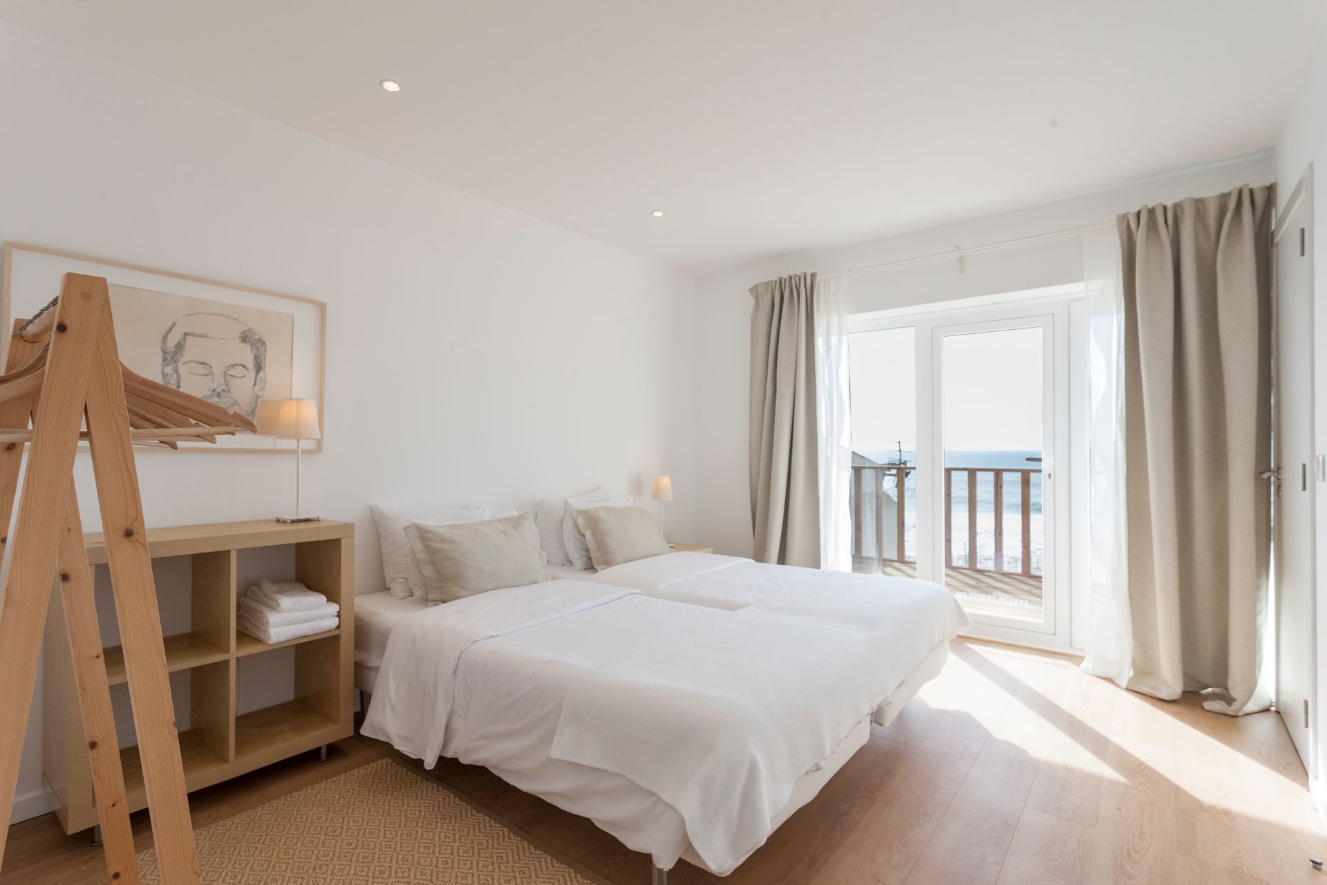 a bedroom with two beds and a balcony with a view of the ocean .